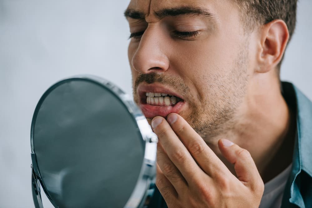 close up view of young man with tooth pain looking