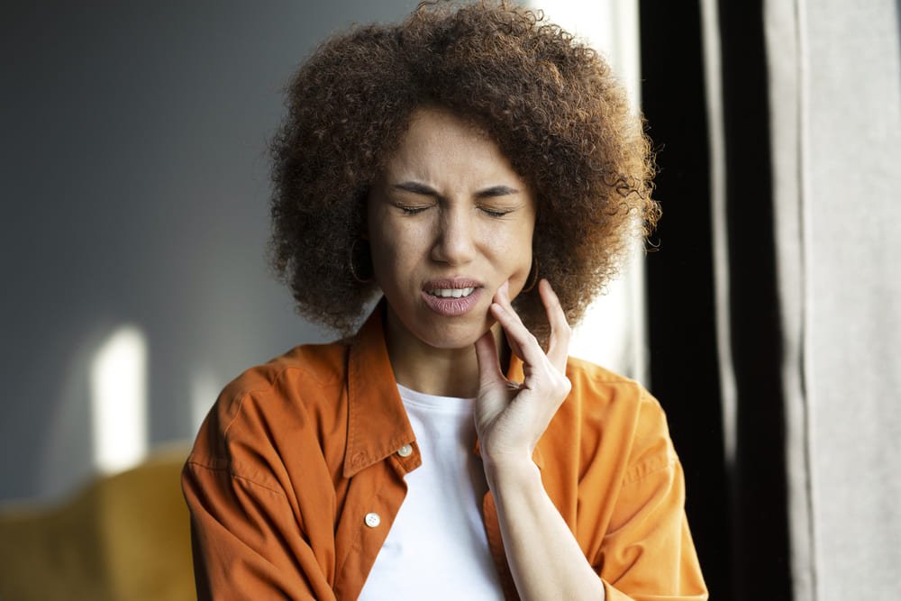 woman holding hand on his cheek having a toothache
